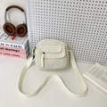 Minimalist beige corduroy crossbody bag with front pocket shown in a lifestyle setting - White