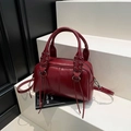 Dunkelrote Boston-Tasche aus glänzendem Leder mit Schnürdetails und langem Schultergurt - Rot