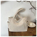 Detalle del bolso tote de pana blanco crudo con bolsillos laterales y nudo trenzado - Blanco Roto