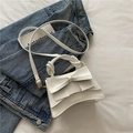 Schicke weiße Ledertasche mit großer Schleife und gedrehtem Griff auf Denim-Hintergrund - Weiß