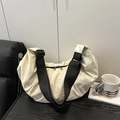 Chic cream dumpling crossbody bag with adjustable wide black strap on wooden surface - White