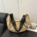 Minimalist beige nylon crossbody dumpling bag with wide black strap on a wooden desk - Khaki