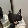 Bolso de hombro en cuero brillante marrón oscuro con detalles dorados y diseño curvo - Marrón