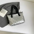 Silberne glänzende Tragetasche mit Schmetterlingsprägung und schwarzen Griffen für Damen - Silber
