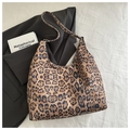Platliggende vintage tote bag met luipaardprint op zwarte blazer en kunstboek decor - Khaki