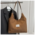 Detail of brown suede tote bag with white fashion label and long shoulder strap - Brown