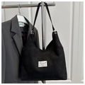 Detail of black corduroy tote bag showing large capacity and fashion label on front - Black