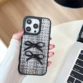 Détail de la coque tissée avec des nœuds noirs et une plaque métallique dorée - iPhone 17 Pro Max / Noir