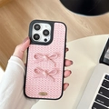 Vue détaillée d'une coque en tweed rose avec deux nœuds 3D et logo en métal doré - iPhone 17 Pro Max / Rose