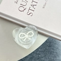Detailed view of heart-shaped transparent phone grip with pearl bow on a minimalist desk - 3D Heart Stand - Bowknot Series - No. 12