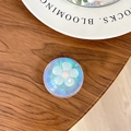 Detailed view of iridescent laser crystal phone grip with white flower on wooden surface - Dreamy Bubble No. 32