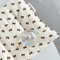 Détail d'un coussin crème aux motifs de nœuds bruns avec une boule de cristal irisante - Support Boule de Cristal-Bulle de Rêve-No.55