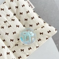 Gros plan sur coussinet en tissu beige avec nœuds bruns et support de téléphone bleu - Support Boule de Cristal-Bulle de Rêve-No.57