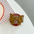 Detailansicht eines braunen Harz-Griptoks mit goldener 3D-Schleife und roter Basis - Braun