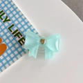 Detail of blue bow-shaped phone grip with golden heart inlay on white background - Large Bowknot French Heart Dark Green