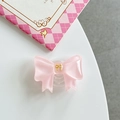 Dettaglio macro del supporto per telefono a fiocco in resina rosa con emblema dorato - Rosa