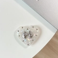Macro shot of pearl heart phone grip with silver bow accent and metallic studs - Transparent Stand Shell Heart Multi-layer Knot