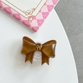 Detailed top view of a brown resin bow phone grip with a golden metal center ornament - Brown