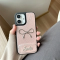 Detail of pink faux leather phone case featuring a silver metal bow and rhinestone Smile text - Pearl Mirror Stand Bowknot (17Promax) / Pink