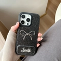Detail of black leather texture phone case with silver metal bow and rhinestone smile charm - Pearl Mirror Stand Bowknot (17Promax) / Black
