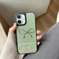 Close-up of sage green leather iPhone case with silver metal bow and rhinestone Smile detail - Green