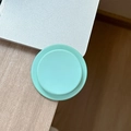 Macro view of mint green matte circular phone socket grip on silver laptop surface - Dark Green