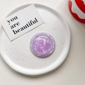 Macro shot of purple marble shell pattern magnetic Magsafe phone grip on a white ceramic plate - Magnetic Model / Violet