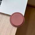Close-up of matte terracotta magnetic phone socket stand on a wooden office desk - Brown
