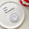 Detalle del soporte MagSafe redondo con elegante textura de nácar en una bandeja decorativa - Modelo Magnético / Blanco