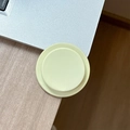 Close-up of a matte pastel yellow magnetic phone grip on a wooden desk background - Yellow