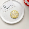 Detailed close-up of a round MagSafe phone grip with yellow shell texture on porcelain - Magnetic Model / Yellow