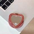 Macro shot of glittery red heart-shaped phone grip with a built-in mirror and star sequins - Brown