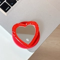 Macro detail of red glitter heart phone socket with star sequins and a compact mirror - Red