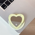 Detail of glitter heart phone grip with mirror on a silver laptop surface - Yellow
