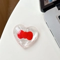 Detail of transparent heart-shaped MagSafe phone socket with red bow on a white desk - Adhesive-Red