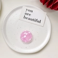 Detalle del soporte para móvil rosa con textura de concha en un plato de cerámica - Soporte de Patrón de Concha - Rosa