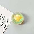 Detail of a transparent phone grip featuring a yellow mini teacup in green glitter liquid - Dreamy Bubble No. 7