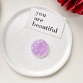 Detailed top view of a purple shell-texture collapsible grip on a white ceramic plate - Shell Pattern Grip - Violet