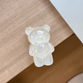 Close-up of a glittery pearl white bear-shaped phone grip on a minimalist wooden desk - Standard Pop Socket Style / Pearlescent Bear - White