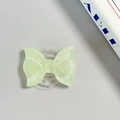Macro view of mint green glitter bow phone grip with clear retractable base on desk - Pearl Adhesive Style / Light Green