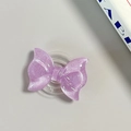 Detailed view of purple glitter bow-shaped MagSafe phone grip with collapsible base - Pearl Adhesive Style / Purple
