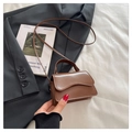 Detailed view of brown leather mini handbag featuring wave-shaped flap on black blazer background - Brown