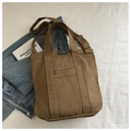 Bruine canvas shopper met brede banden en ritsvak op witte gestructureerde achtergrond - Bruin