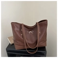 Detail of dark brown tote bag with golden bow hardware and fine leather texture - Brown