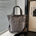 Minimalist grey canvas tote bag with adjustable shoulder strap and fashion label detail - Gray