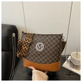 Detail einer braunen Monogramm-Beuteltasche mit goldenem M-Logo und gewebtem Tragegurt - Kaffeebraun