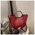Detail of red faux leather bucket bag with vertical piping and gold-toned hardware - Red