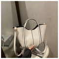 Close-up of white bucket bag with black contrast edges and golden hardware details - White