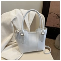 Détail du sac à main blanc avec coutures verticales et anneaux dorés élégants sur chaise - Blanc