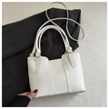 Primer plano de un bolso tote blanco sobre un blazer negro mostrando costuras y herrajes dorados - Blanco